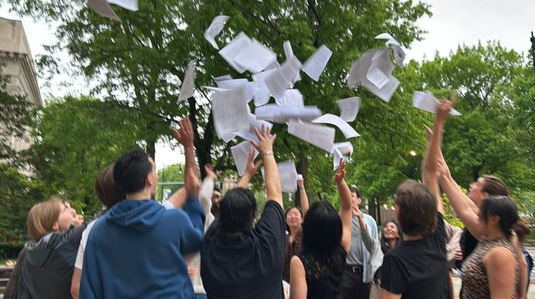 Group photo of students throwing papers up in the air in celebration